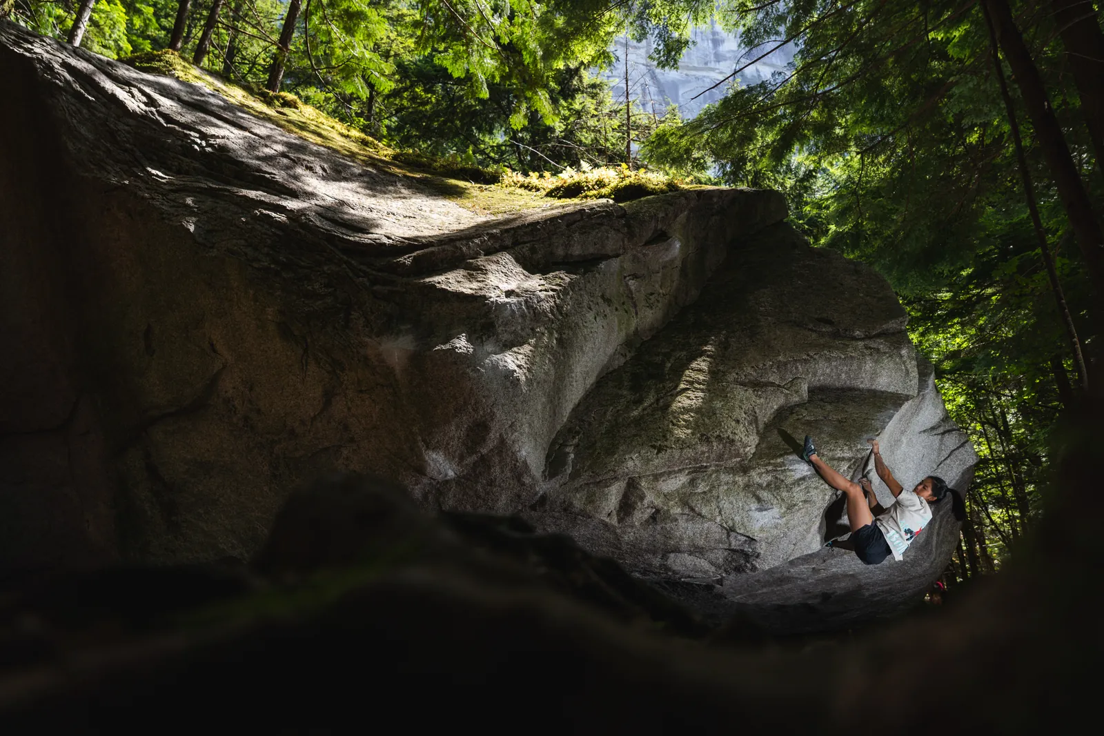 Boulderer climbing a granite overhang in the Squamish forest