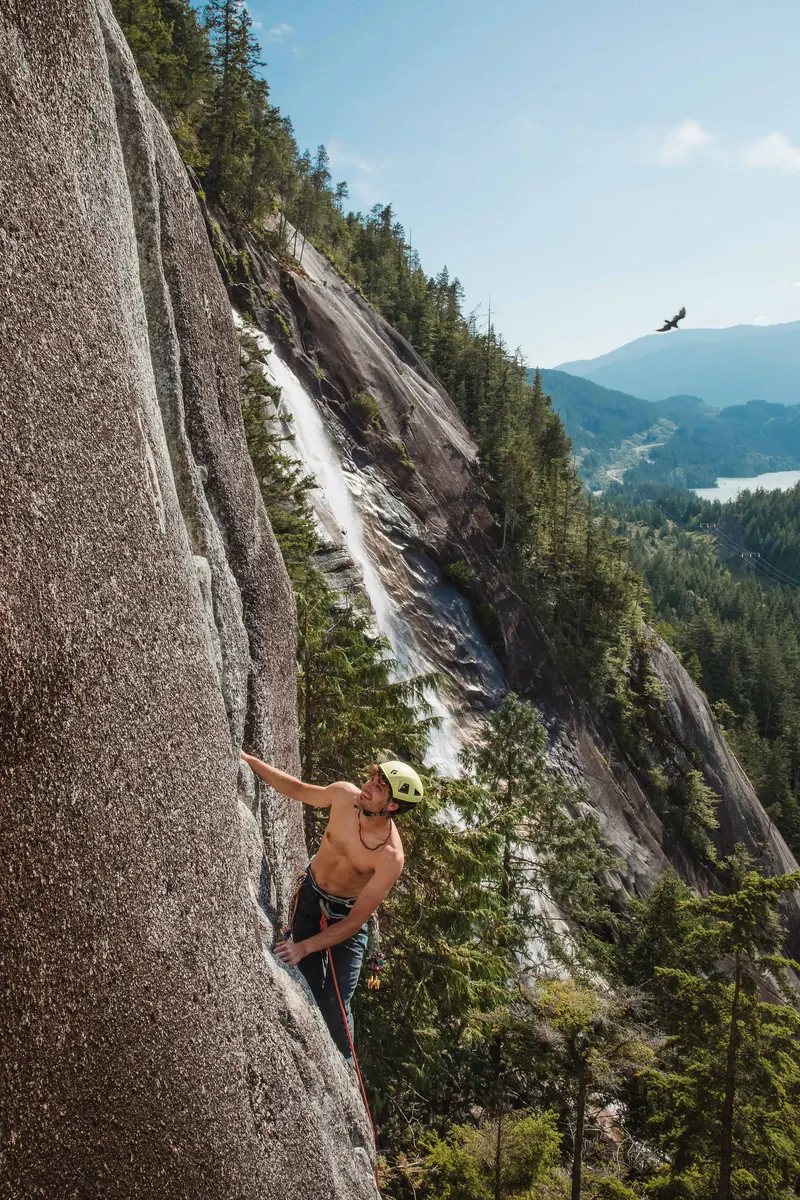 Belayer and climber at the base of a Squamish crag surrounded by old-growth trees