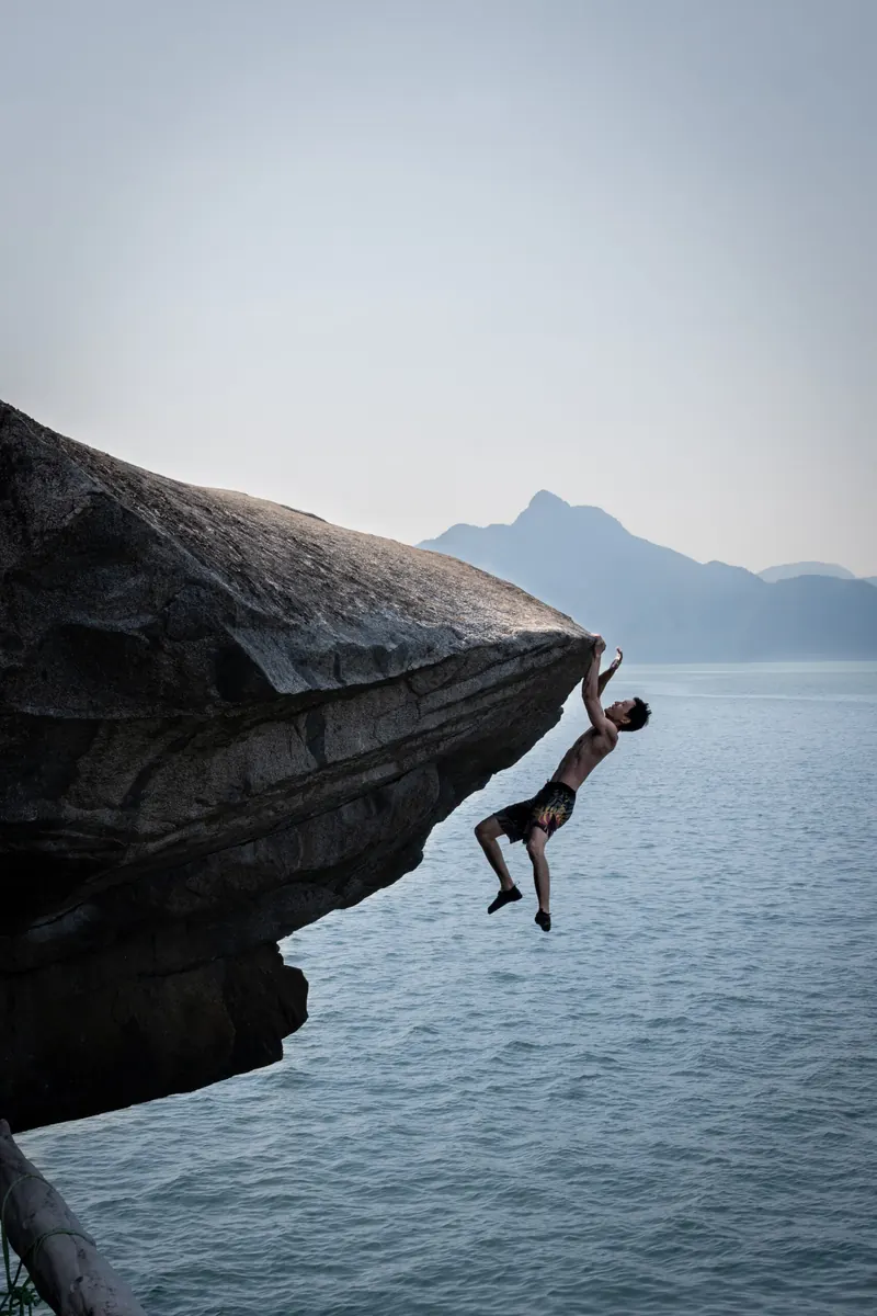 Climber ascending a vertical crack route with Howe Sound visible in the background