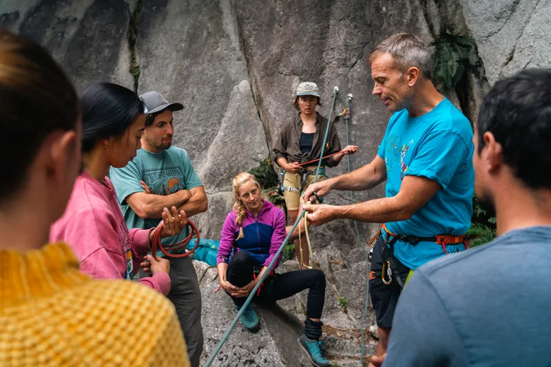 Climbing guide demonstrating rope techniques to a group of climbers at a Squamish granite crag