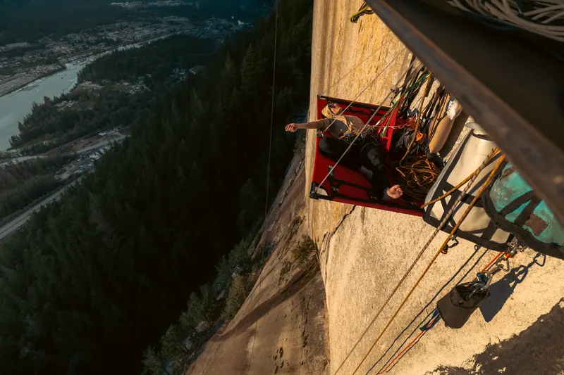 Boulderer reaching for a hold on a granite overhang in the Squamish forest